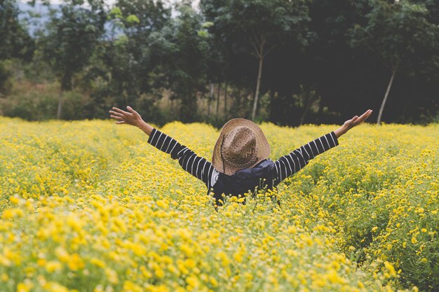 Frau hebt ihre Hand im gelben Chrysanthemenblumenfeld und fühlt sich glücklich und frei