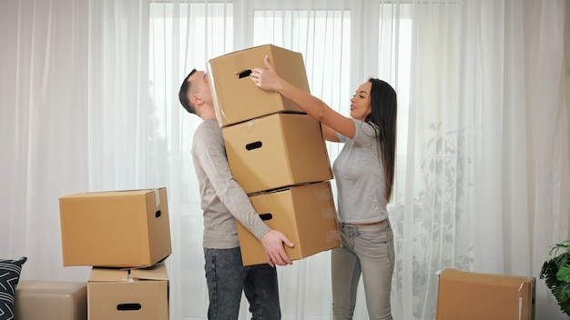 Frau hilft Ehemann beim Tragen von Paketen in neuer Wohnung
