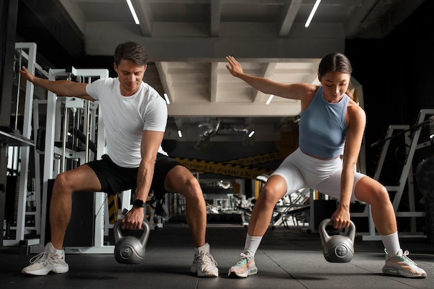 Foto frau hilft mann im fitnessstudio