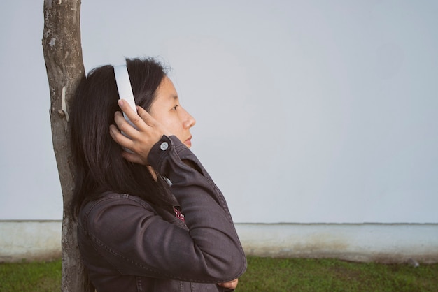 Frau hört Musik auf einem Baum auf der Straße