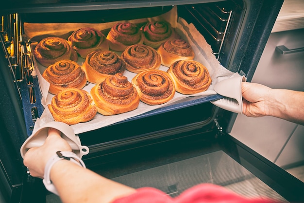 Frau holt Deko mit frischer Bäckerei aus dem Ofen heraus