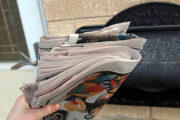 Frau holt Zeitungsstapel aus einem Briefkasten draußen
