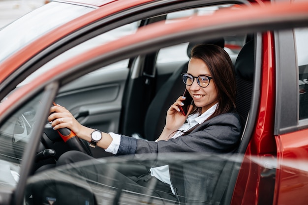 Frau im Auto hinter dem Lenkrad, das am Telefon spricht