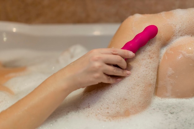 Frau im Bad hält einen Vibrator in der Hand