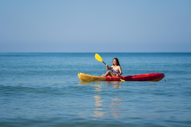 Frau im Badeanzug, die ein Kajakboot im Meer paddelt