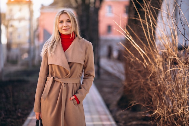 Frau im beige Mantel, der im Park steht