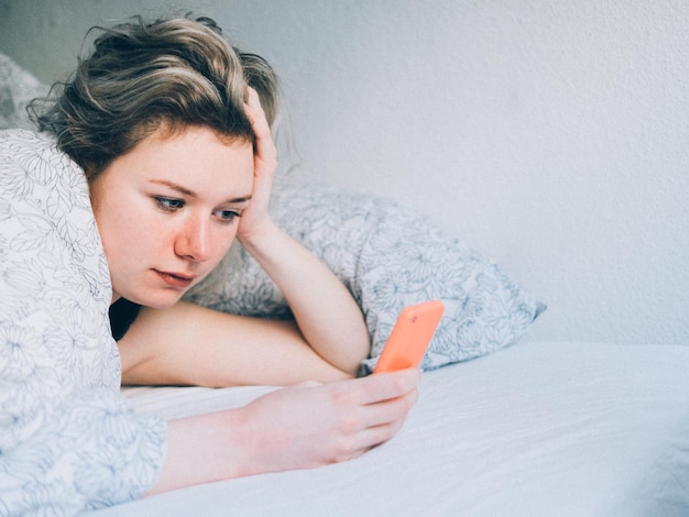 Frau im Bett mit Telefon