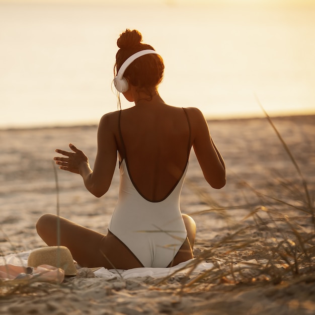 Frau im Bikini, die Musik mit Kopfhörern auf Natur genießt