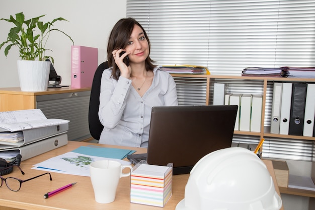 Frau im Büro, die auf Handy am Geschäftsplatz spricht