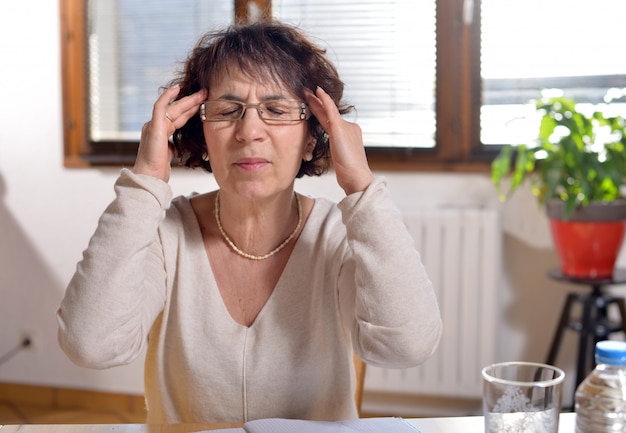 Frau im Büro hat Kopfschmerzen