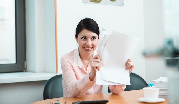 Frau im Büro mit zerknittertem Papier. Konzept des Bürolebens.