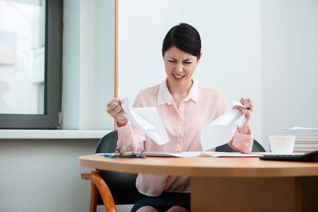 Frau im Büro mit zerknittertem Papier. Konzept des Bürolebens.