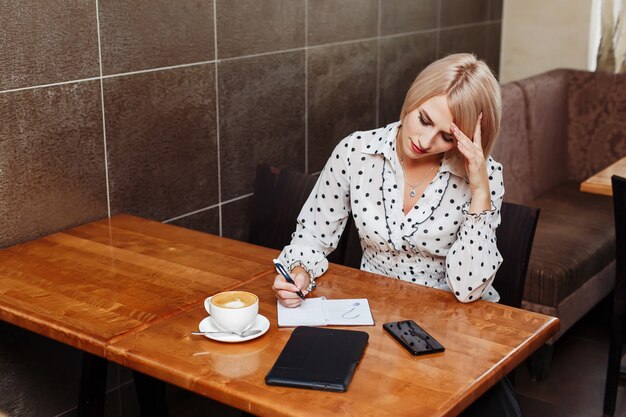 Frau im Café, das in Notizbuch sitzt und schreibt