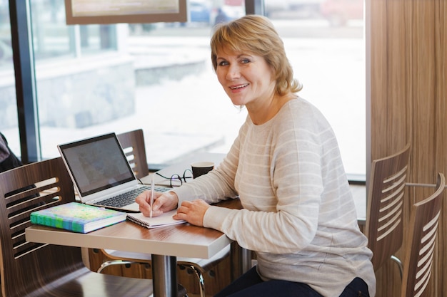 Frau im Café und im Büro, die mit Laptop arbeitet