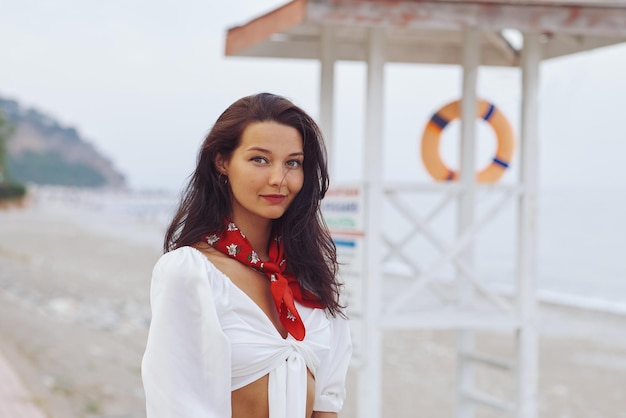 Frau im eleganten Strandoutfit im Freien gegen die Küste im Hintergrund während der Sommerferien