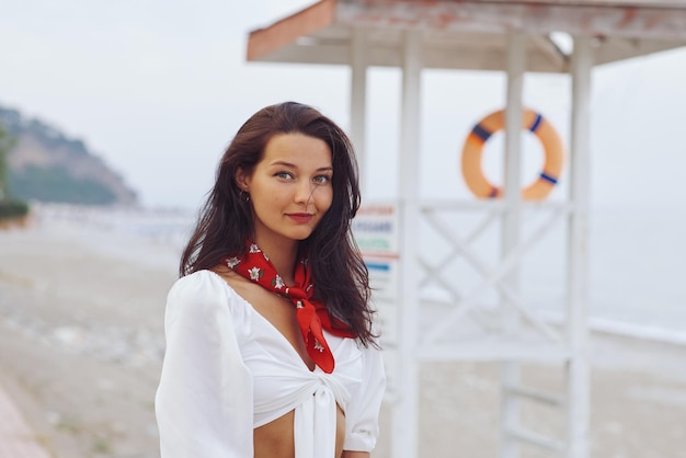 Frau im eleganten strandoutfit im freien gegen die küste im hintergrund während der sommerferien