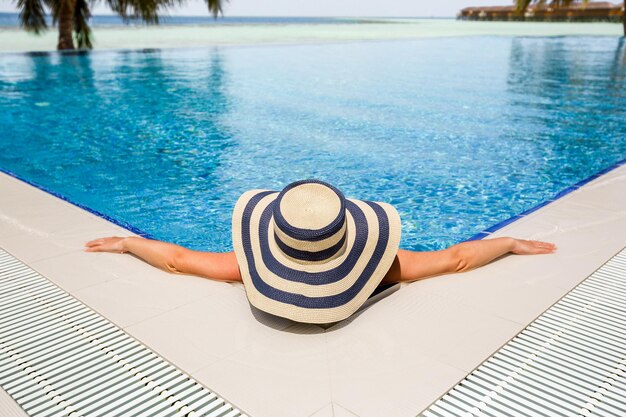 Frau im entspannenden Swimmingpool des Strohhutes. Untere Komposition, perfekter Kopierraum für Ihre Textanzeigen.