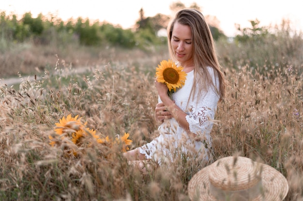 Foto frau im feld, die sonnenblume hält