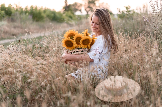 Foto frau im feld, die sonnenblumenstrauß hält