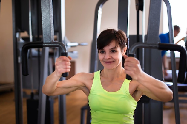 Frau im Fitnessstudio beim Krafttraining am Simulator