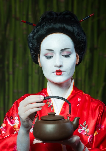 Frau im Geisha-Make-up mit Tonteekanne