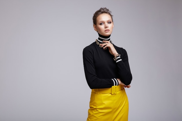 Frau im gelben Lederrock schwarze Bluse Accessoires Stiefel auf weißem Hintergrund Studio Shot