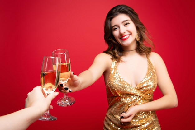 Frau im goldenen Kleid mit rotem Lippenstift und Champagner in der Hand