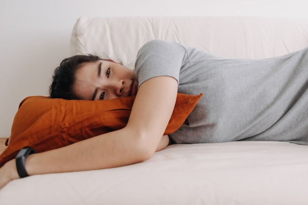 Frau im grauen Kleid schläft und entspannt auf dem Sofa in der Wohnung