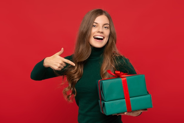 Foto frau im grünen pullover zeigt auf weihnachtsgeschenk