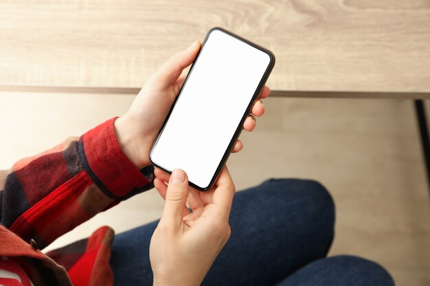 Frau im Hemd und in den Jeans, die Telefon mit leerem Bildschirm halten