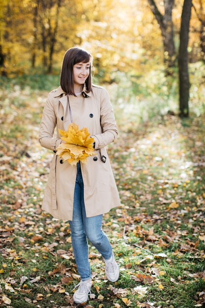 Frau im Herbstwald mit Blättern in den Händen Die Frau ist glücklich