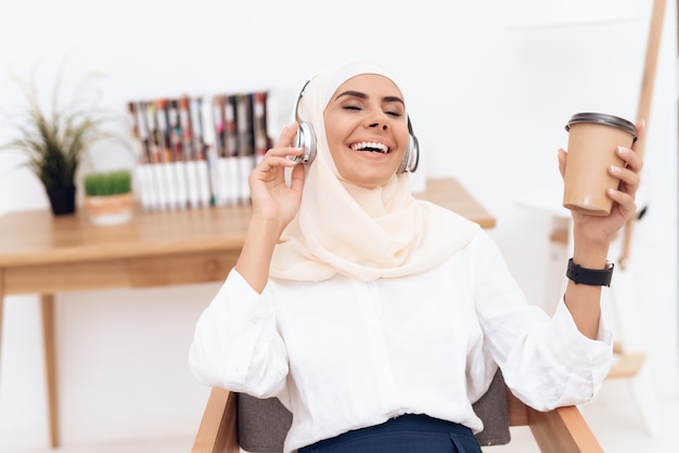 Frau im Hijab hört Musik über Kopfhörer.