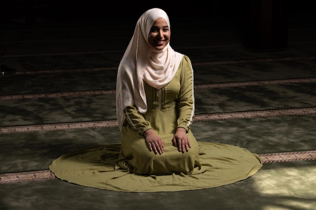 Frau im Hijab sitzt in der Moschee und betet