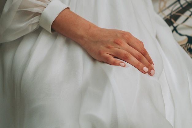 Frau im Hochzeitskleid mit der Hand am Knie
