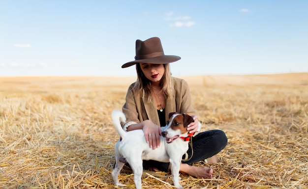 Frau im Hut mit Hund auf Weizenfeld