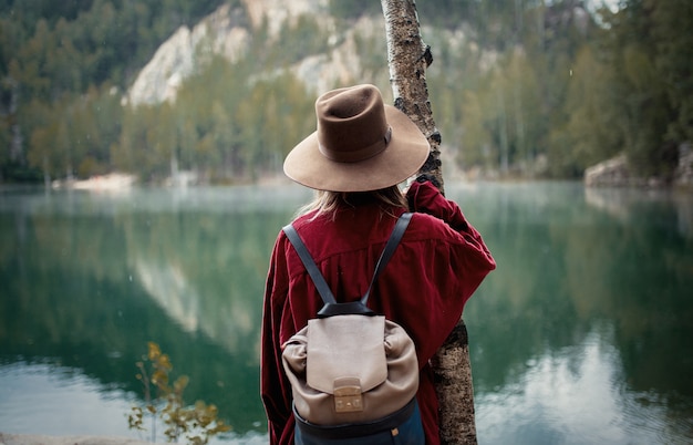 Frau im Hut und im roten Hemd nahe See in Berge.