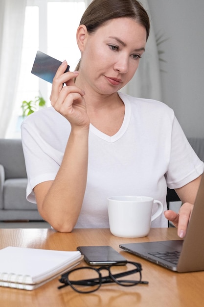 Frau im jungen oder mittleren Alter, echte Frau, die Kreditkarte für Online-Zahlung hält Konzept des Remote-Arbeitsplatzes und Arbeiten bei homexA