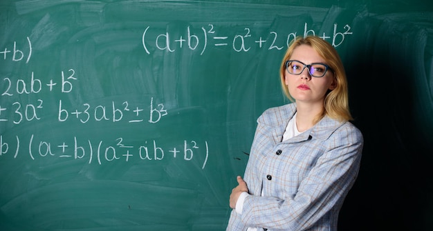 Frau im Klassenzimmer Lehrer im Schulunterricht an der Tafel Zurück zur Schule Lehrertag Studium und Bildung Moderne Schule Wissenstag Zuversichtlich in ihrer erfolgreichen Zukunft ernsthafte Frau