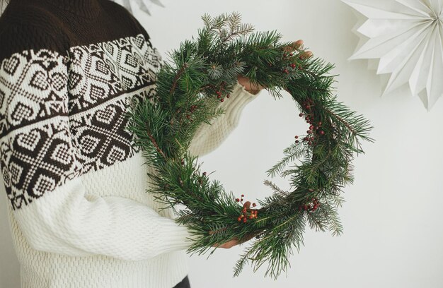 Foto frau im kuscheligen pullover mit rustikalen weihnachtskränzenskandinavische winterferien frohe weihnachten
