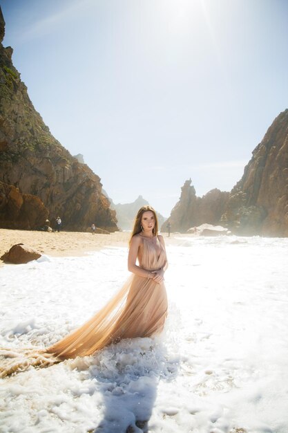 Frau im langen Kleid nahe Felsen und Ozean