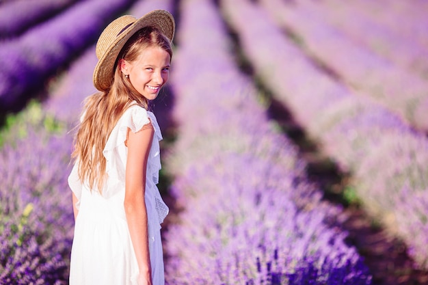 Frau im Lavendelblumenfeld bei Sonnenuntergang im weißen Kleid und im Hut