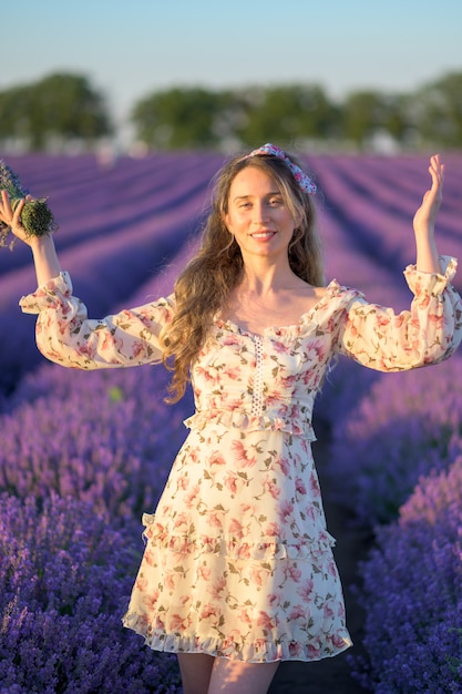 Frau im Lavendelfeld bei Sonnenuntergang, der Sommerkleid trägt