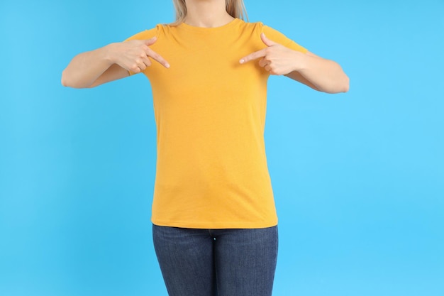 Frau im leeren orangefarbenen T-Shirt auf blauem Hintergrund