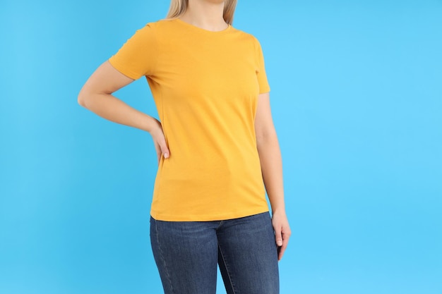 Frau im leeren orangefarbenen T-Shirt auf blauem Hintergrund