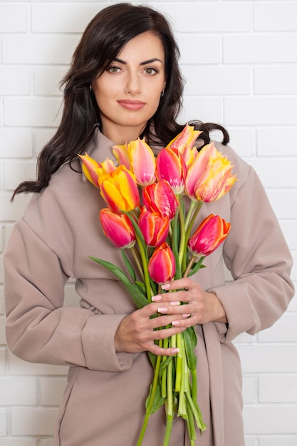 Frau im Mantel mit Blumenstrauß