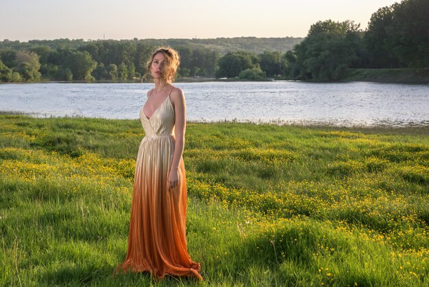 Frau im orange Kleid bei Sonnenuntergang