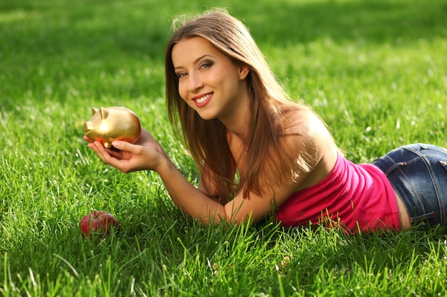 Frau im Park auf dem grünen Gras mit Sparbüchse