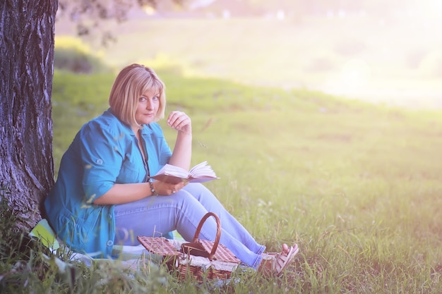 Frau im Park bei Sonnenuntergang mit Buch