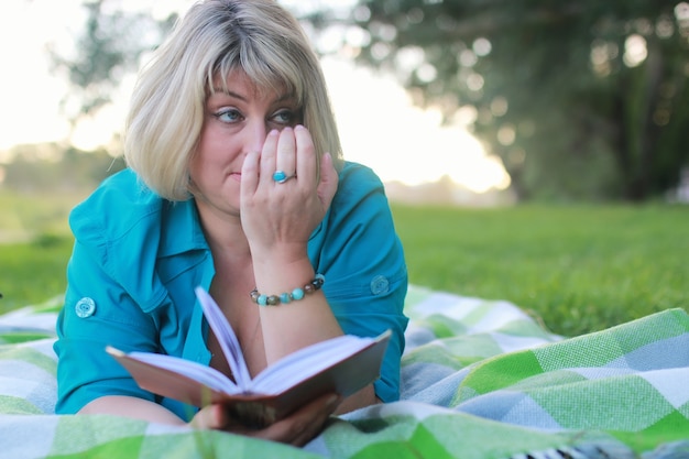 Frau im Park mit Buch auf dem Gras