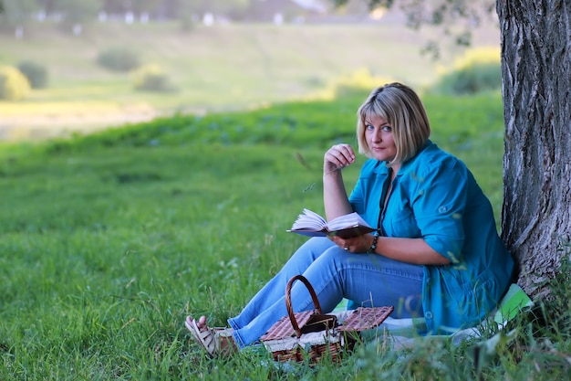 Frau im Parkbaum liest Buch